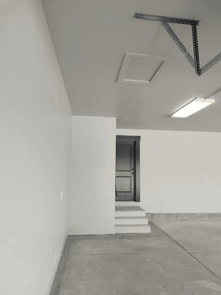Professional drywall installation showing clean finished walls and ceiling in garage space